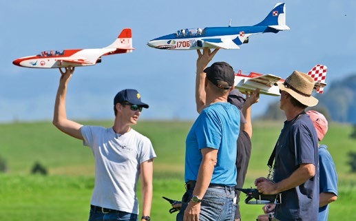 A group of people holding up model aircraft, including a blue and white model with the number 1706.