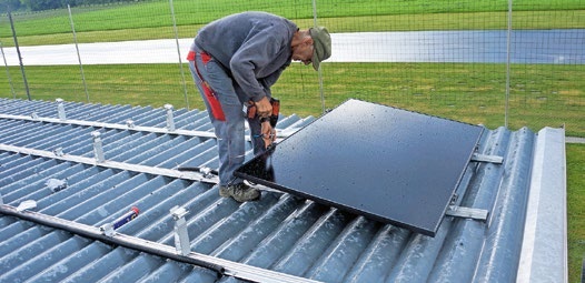 Josef montiert das erste PV-Panel auf dem Dach.