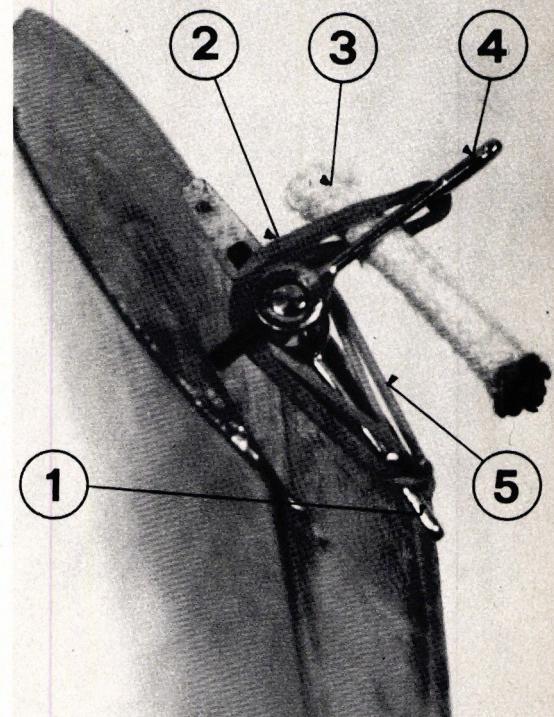 Abb. 1: Wendekursvorrichtung (Situation beim Start). A black and white photograph showing the control mechanism of a model airplane at the start of a flight. The rudder is in a neutral position. Five numbered callouts point to various components: 1 points to a small metal clip on the rudder axis; 2 points to a rubber band; 3 points to a thin string; 4 points to a small metal clip on the rudder; 5 points to a rubber band.