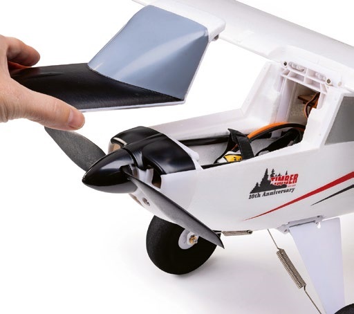 Close-up view of the E-Flite Timber 1.5 M 10th Anniversary Special Edition RC airplane, showing the top hatch being opened to reveal the internal battery compartment and electronics.
