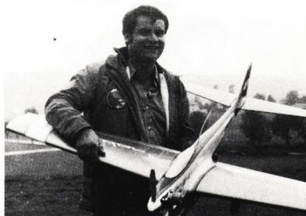 A man standing next to a model airplane, smiling.