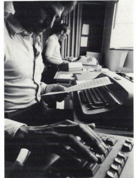 A black and white photograph showing a person's hands operating a computer terminal, likely for data processing during the event.