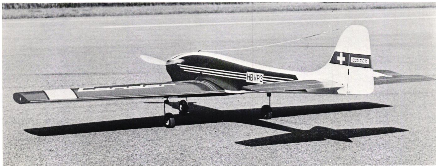 A black and white photograph of a model airplane, the Condor, on a paved surface. The aircraft is a low-wing model with a long, slender fuselage and a large tail. It has a Swiss cross logo on the tail and the word 'CONDOR' written on the side of the fuselage. The registration number 'HBVP3' is visible on the side of the fuselage.