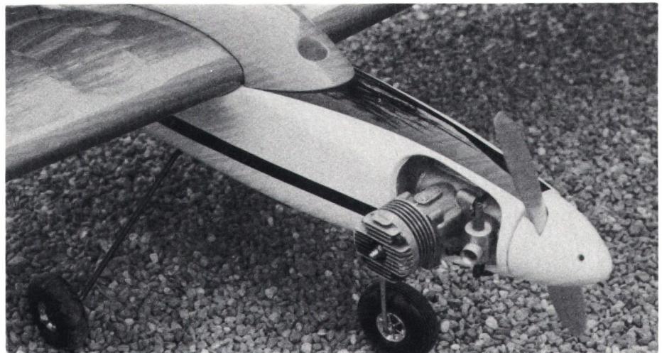 Close-up photograph of the engine and propeller assembly of a model aircraft, showing the engine block and the propeller blades.